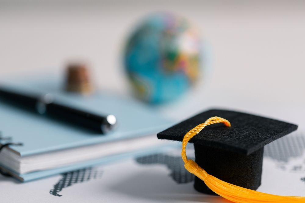 Birrete de graduación junto a libros y un globo terráqueo